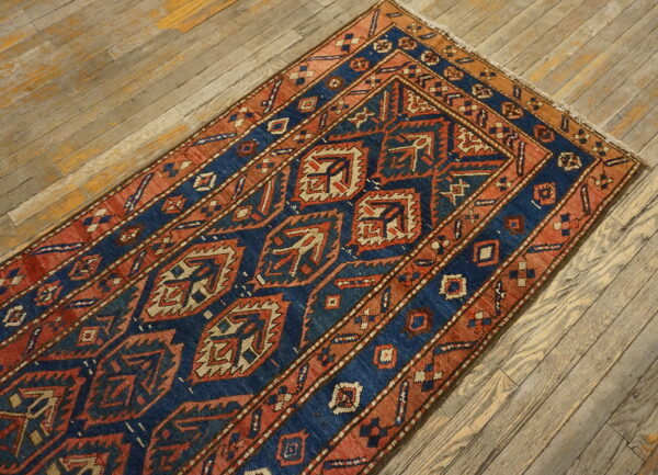 Blue and rust geometric runner rug with a repeating pattern on rustic wooden plank flooring.