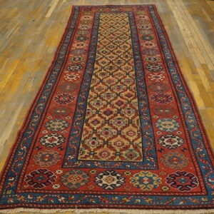 A long runner rug featuring red, blue, and gold geometric patterns sits on aged wooden floorboards.