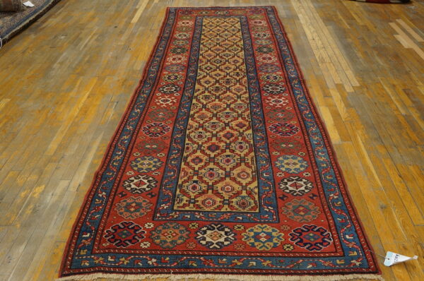 A long runner rug featuring red, blue, and gold geometric patterns sits on aged wooden floorboards.