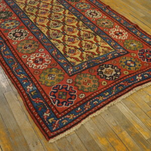 Red, blue, and yellow geometric runner rug with low pile rests on worn, wide plank wood floors.