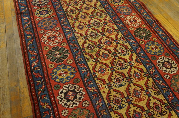 Rust red and mustard yellow runner with tribal geometric patterns sits on rustic hardwood floors.