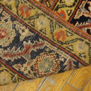 Close-up showing the reverse of a tightly woven, low-pile traditional rug on golden wood flooring.
