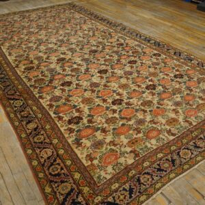 Rectangular low-pile rug with coral and purple floral motifs and dark patterned borders on wooden flooring.