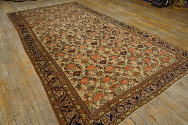 Rectangular low-pile rug with coral and purple floral motifs and dark patterned borders on wooden flooring.