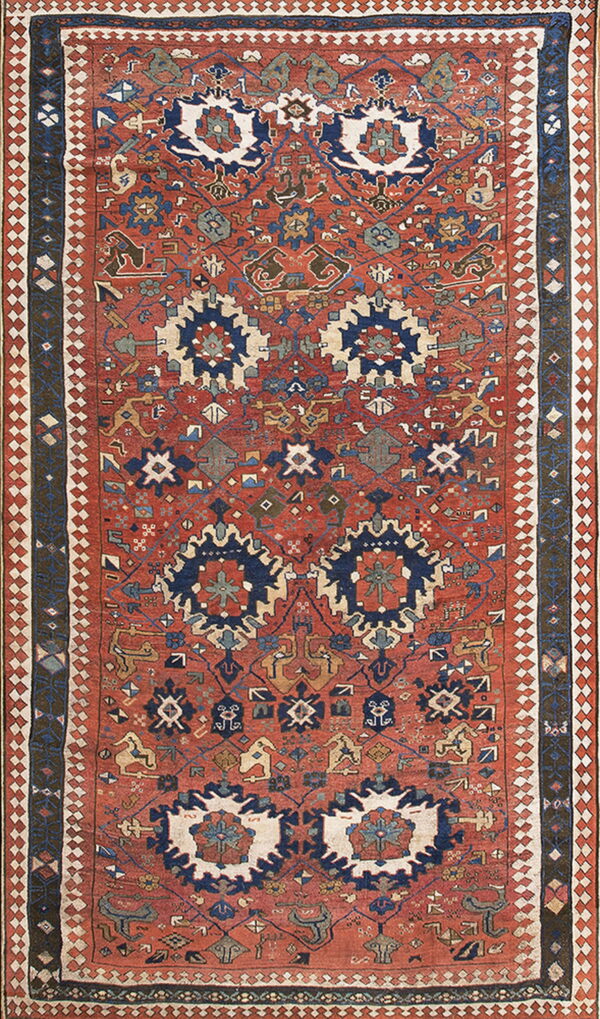 Geometric low-pile rug featuring a rusty red field densely covered in navy blue, cream, and gold motifs.