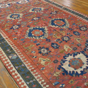 Rust and indigo geometric rug with a detailed border displays tribal patterns on wood flooring.
