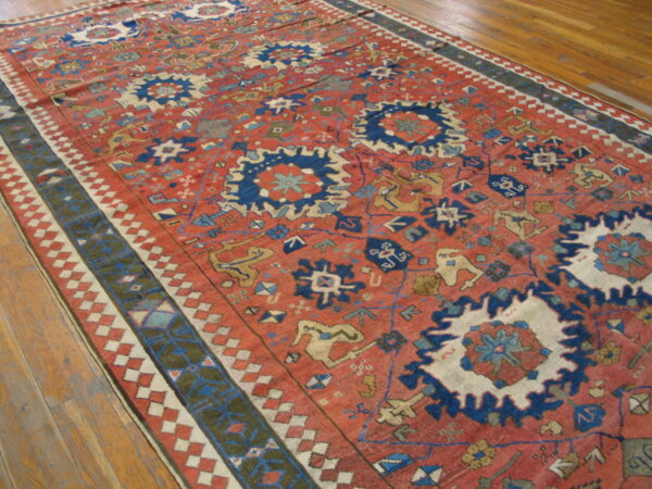 Rust and indigo geometric rug with a detailed border displays tribal patterns on wood flooring.