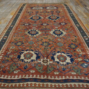 Terracotta and navy blue patterned rug with multiple geometric borders displayed on worn wood planks.