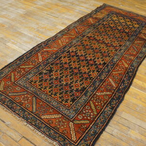 Geometric runner rug in terracotta, navy, and black with visible low pile texture on light wood planks.