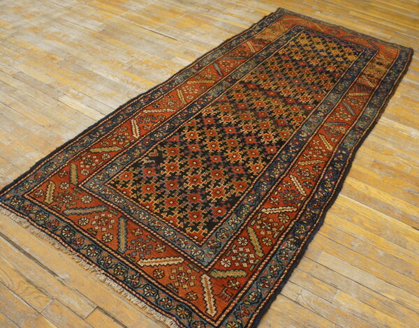 Geometric runner rug in terracotta, navy, and black with visible low pile texture on light wood planks.