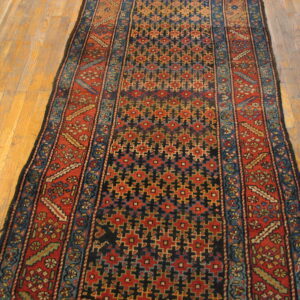 Narrow runner in deep red, navy, and teal geometric patterns rests on a warm wood floor.