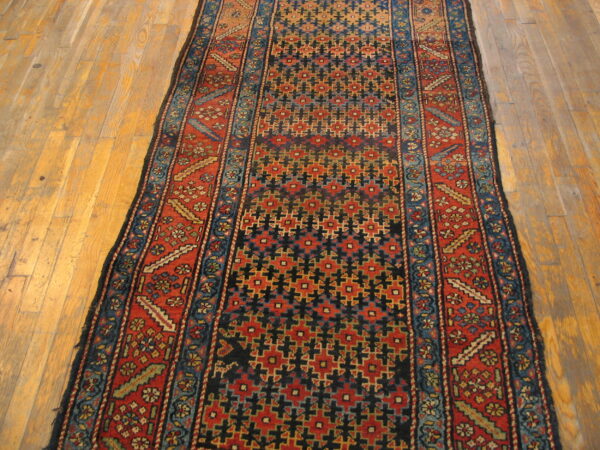 Narrow runner in deep red, navy, and teal geometric patterns rests on a warm wood floor.