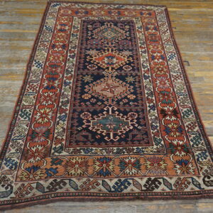 Traditional navy and terracotta rug featuring a detailed geometric pattern laid on distressed wood planks.