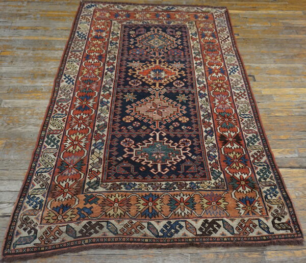 Traditional navy and terracotta rug featuring a detailed geometric pattern laid on distressed wood planks.