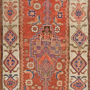 Red and blue geometric tribal rug featuring a stepped central motif and wide beige borders.
