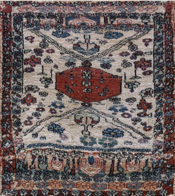 A textured beige rug featuring a central red geometric design surrounded by blue and rust motifs.