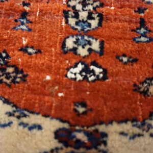 High-pile rug surface displaying geometric motifs in terracotta, cream, navy, and light blue.