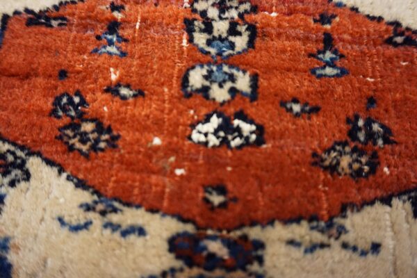 High-pile rug surface displaying geometric motifs in terracotta, cream, navy, and light blue.