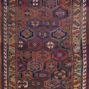 Low-pile rug displaying complex geometric and diamond motifs in deep red, navy blue, and ochre gold.