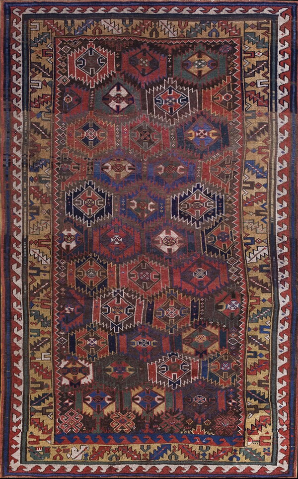 Low-pile rug displaying complex geometric and diamond motifs in deep red, navy blue, and ochre gold.