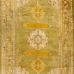 Full view of an olive green rug with visible abrash, detailed floral borders, and gold central medallions.