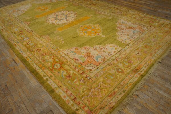 Green high-pile rug with yellow and light-colored traditional floral patterns on rustic wood floor.