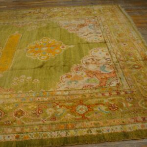 Lime green ornate rug with yellow, peach, and blue accents lying on light brown wood plank flooring.