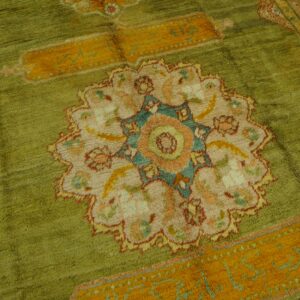 High-pile olive green rug displaying a central medallion design with orange, pink, cream, and teal accents.