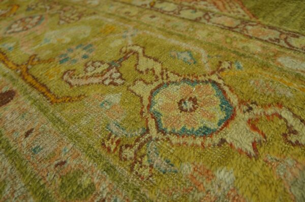 Fuzzy high-pile rug detail featuring an ornate pattern in olive green, peach, and rusty red.