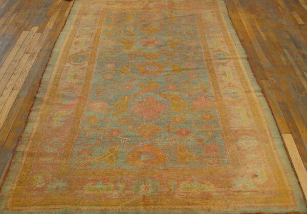 Faded blue and coral runner rug with traditional motifs resting on rustic wooden floorboards.
