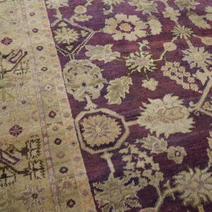 High pile rug featuring beige floral patterns on a deep purple field next to rustic wood floors.