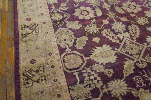 High pile rug featuring beige floral patterns on a deep purple field next to rustic wood floors.