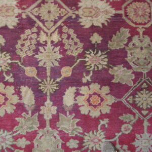 Stylized floral patterned rug in rich magenta and taupe, with a slipper visible in the bottom corner.