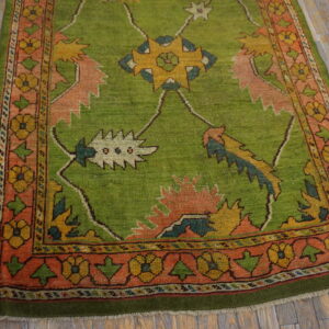A bright green rug with yellow and pink geometric floral designs rests on distressed wooden planks.