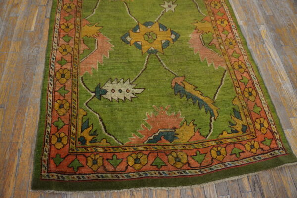 A bright green rug with yellow and pink geometric floral designs rests on distressed wooden planks.