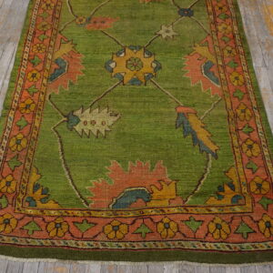 Low-pile rug in lime green featuring geometric floral motifs in orange and gold on weathered wooden planks.