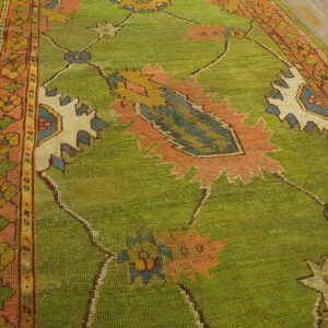 Bright green runner rug with salmon borders and large motifs on worn wood flooring.