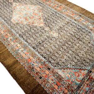 An oblong traditional rug featuring a dark diamond pattern field with coral and teal patterned borders.