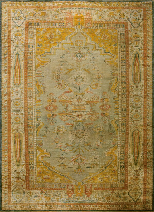 Rectangular traditional rug featuring a pale sage green field, mustard yellow designs, and rust orange borders.