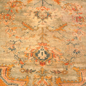 Distressed low-pile rug featuring a traditional orange, navy, and beige pattern on a gray-green field.