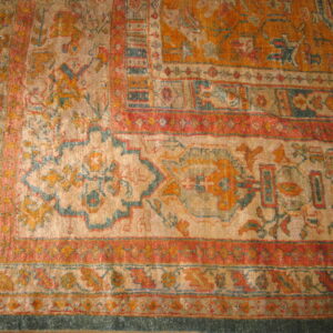 Shaggy rug with rust, gold, and teal traditional motifs visible at the corner on wood planks.