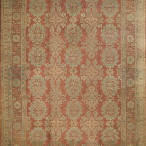 Muted terracotta rug with an intricate repeating damask pattern in faded blue-green and tan colors.