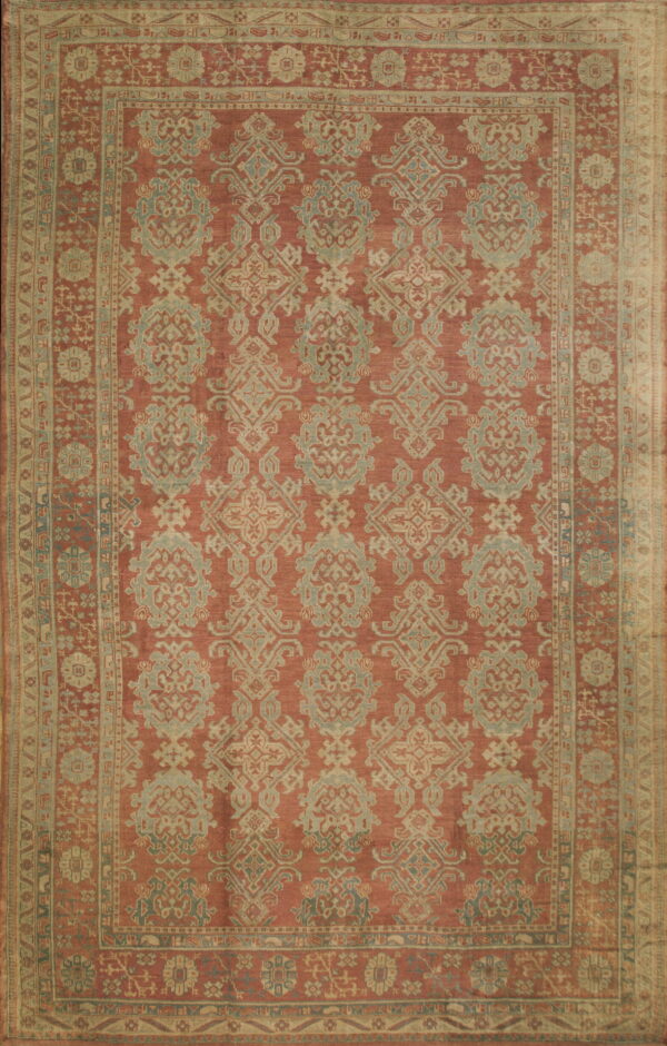 Muted terracotta rug with an intricate repeating damask pattern in faded blue-green and tan colors.
