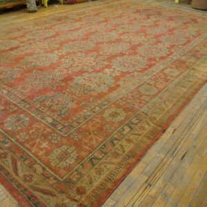 Muted terracotta and pale blue patterned rug on worn yellow wood flooring.