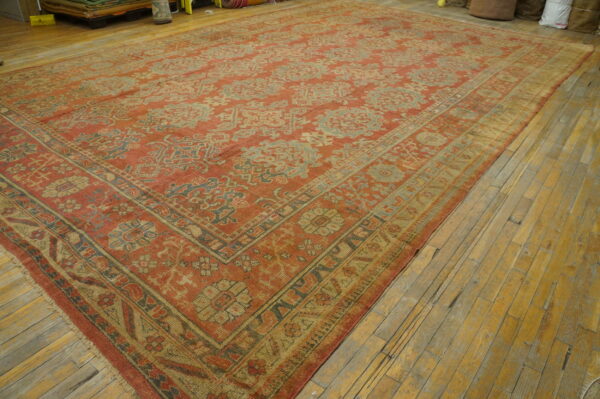 Muted terracotta and pale blue patterned rug on worn yellow wood flooring.