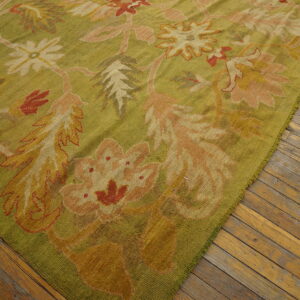 Low-pile olive green rug featuring a large-scale floral pattern in blush, terracotta, and gold on wood flooring.