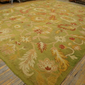 A large chartreuse rug with an ornate floral pattern in rust, gold, and pink lies on wooden floors.