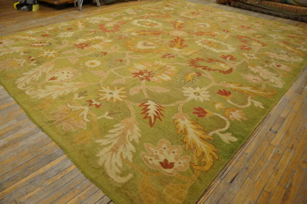 A large chartreuse rug with an ornate floral pattern in rust, gold, and pink lies on wooden floors.