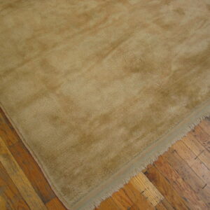 A high-pile beige rug with visible fringe rests on rustic, worn hardwood flooring.