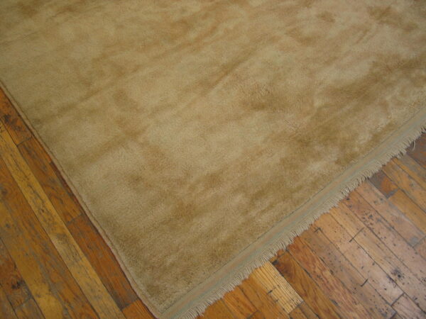 A high-pile beige rug with visible fringe rests on rustic, worn hardwood flooring.